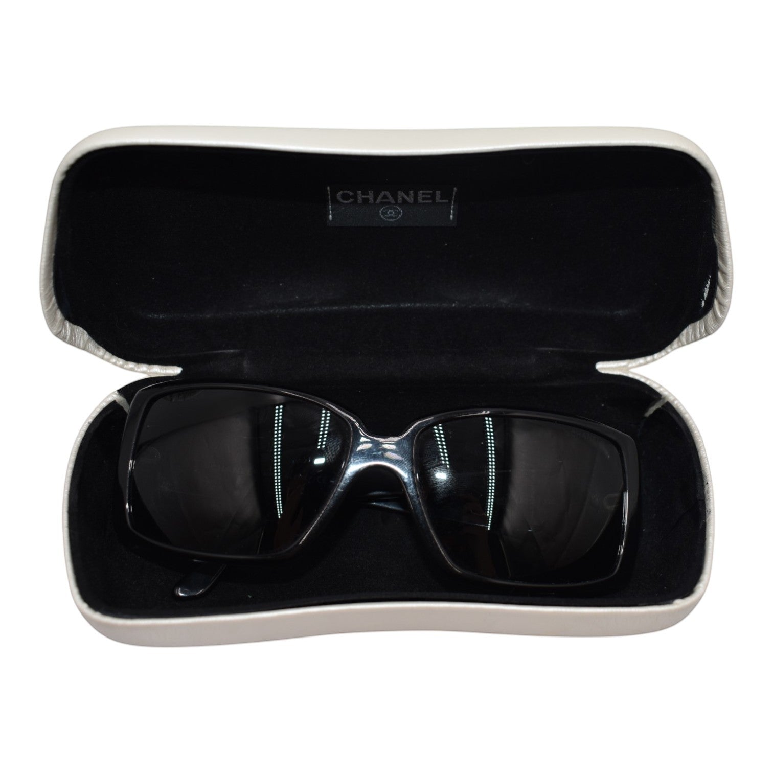 Soldi black baguette crystal logo sunglasses in a white case with black interior and Chanel logo.