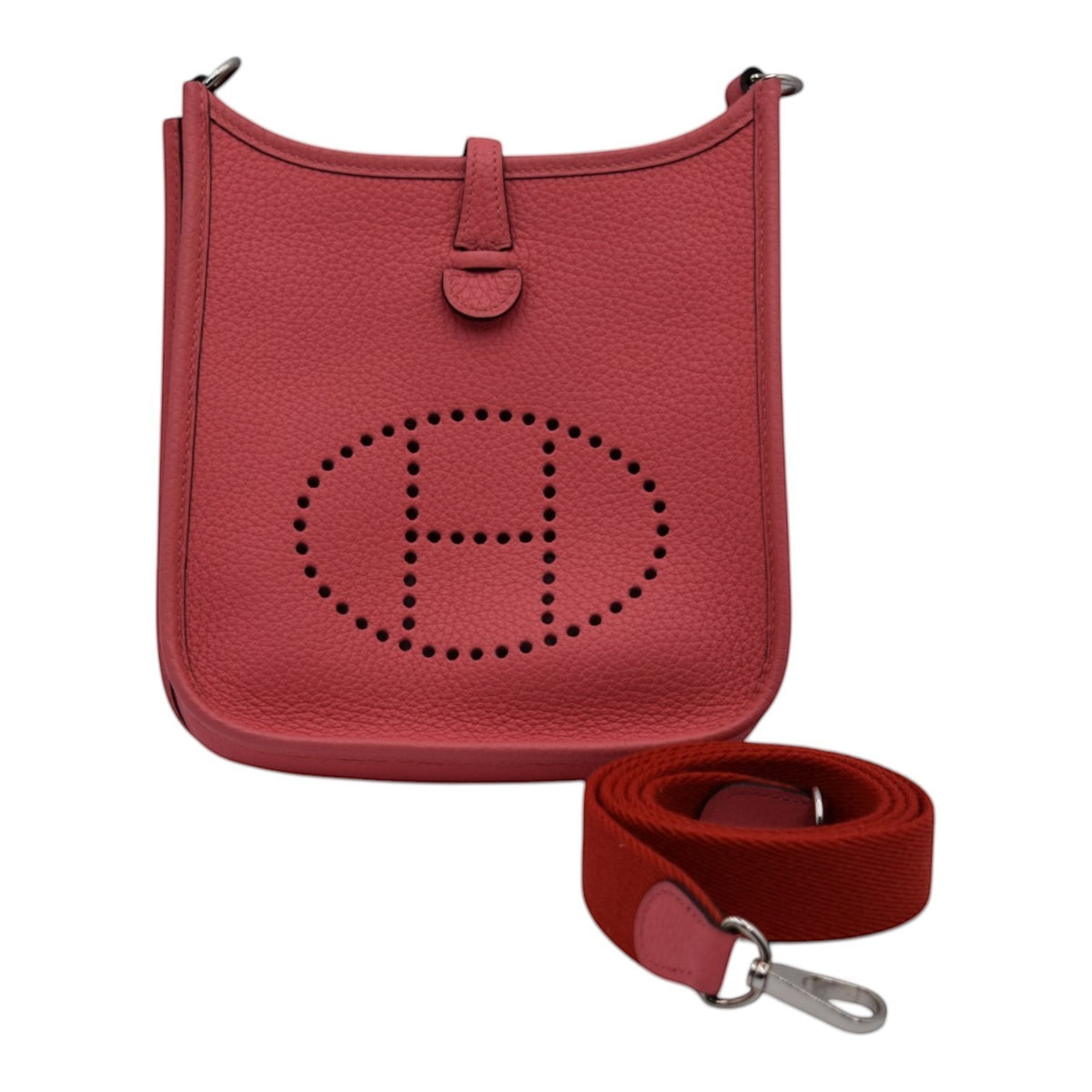Soldi Hermes Mini Evelyn bag in pink pebbled leather with perforated H logo and red canvas strap.