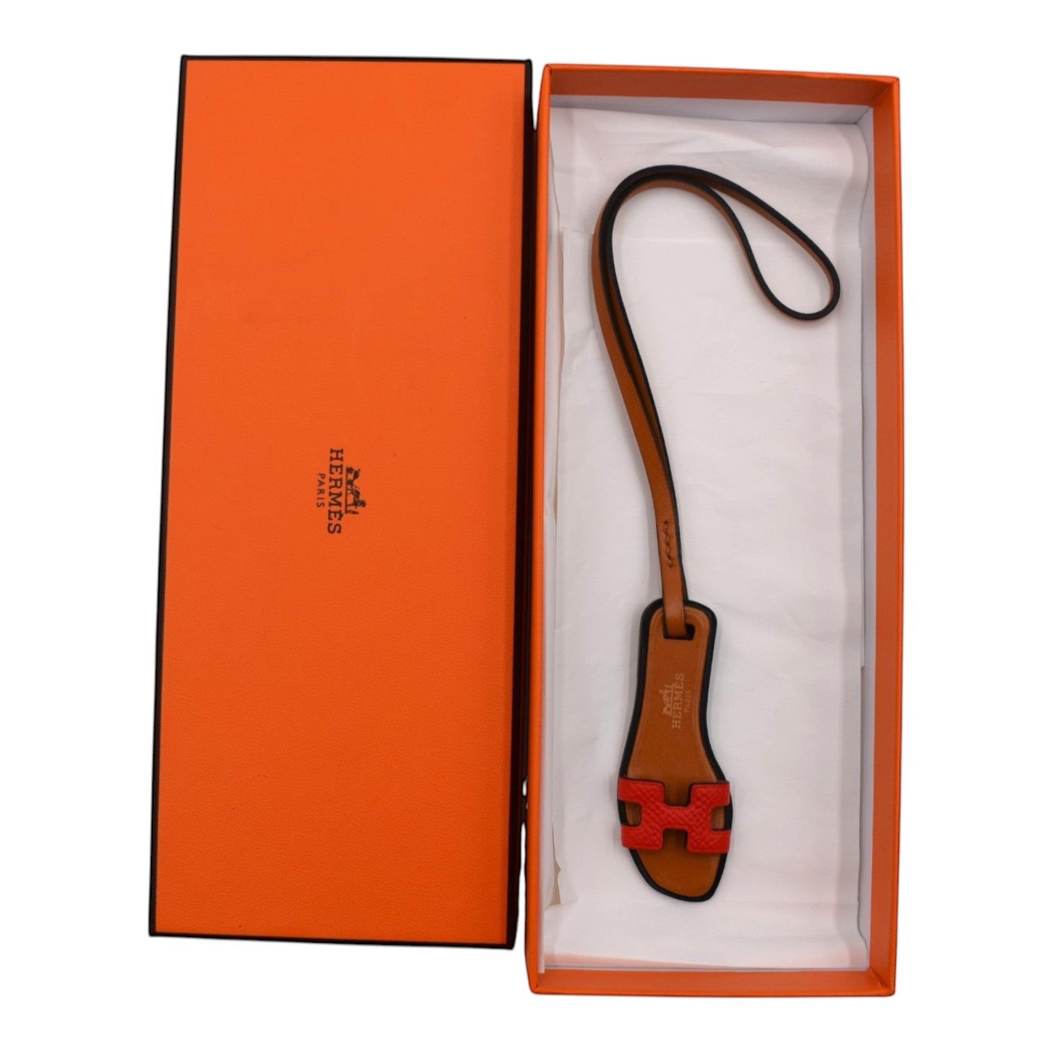 Soldi Oran Charm Red leather sandal charm with H detail and strap, presented in an orange box.